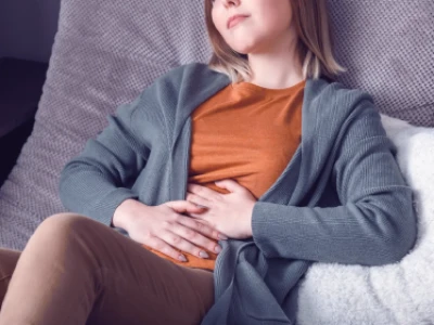 Kobieta leży i trzyma dłonie na brzuchu