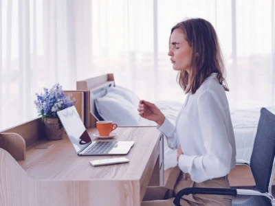 Kobieta z bólem brzucha siedzi przy biurku