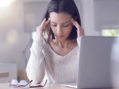 Kobieta z bólem siedzi przy biurku