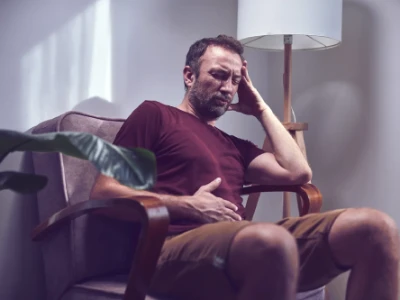 Mężczyzna z bólem brzucha siedzi na fotelu