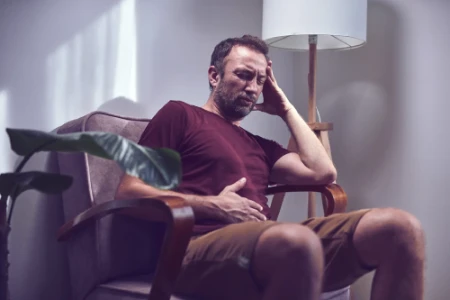 Mężczyzna z bólem brzucha siedzi na fotelu